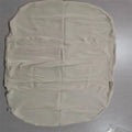 Beige portable baby nest crib cot for newborn infant on a bed