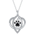 Close-up of a copper necklace pendant showing detailed cat and dog paw prints on a cross chain.