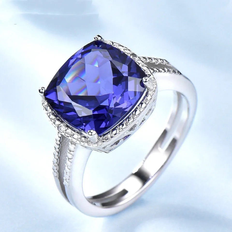 Women's sterling silver ring with oval blue Tanzanite gemstone on a finger.