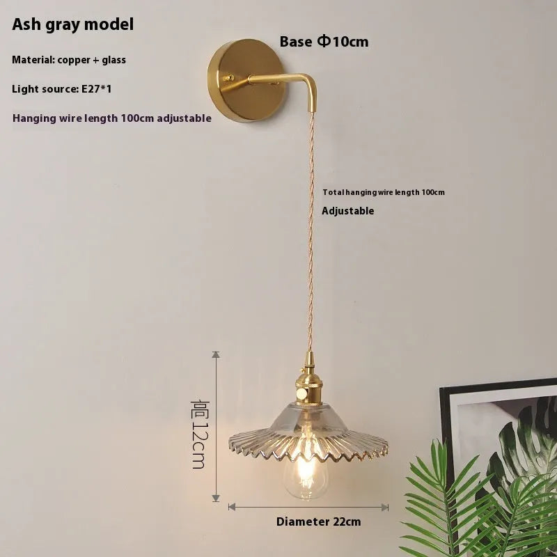 Brass lotus-shaped wall lamp with glass shade in choice of six colours on a plain wall.