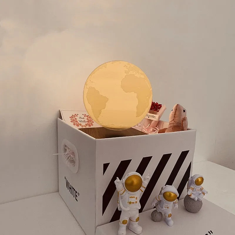 Maglev floating moon and earth night light with LED glow and small astronaut figurines on a table.