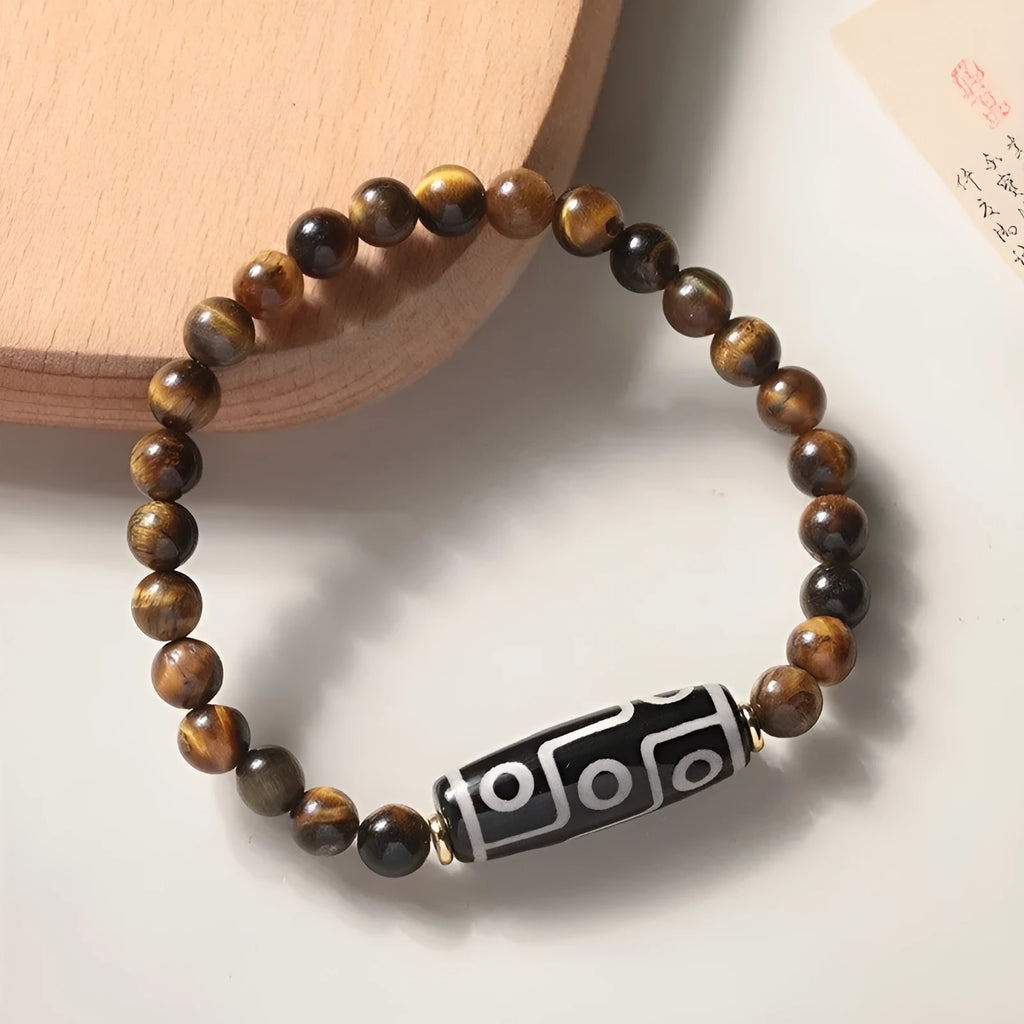 Close-up of a single-circle beaded Buddha rosary bracelet with tigereye dzi patterns on brown beads.