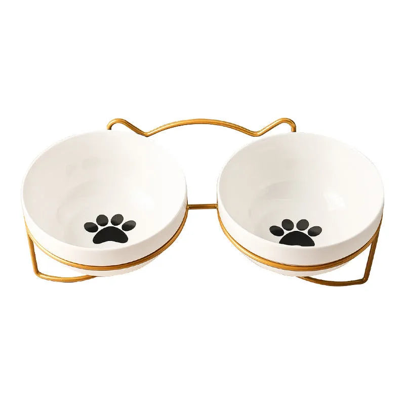 White ceramic pet bowl with cat paw design on a black metal stand with cat ear details.