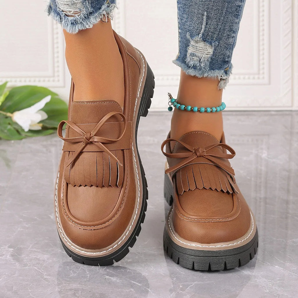 Women's black plus size loafers with tassel decoration and a chunky rubber sole.