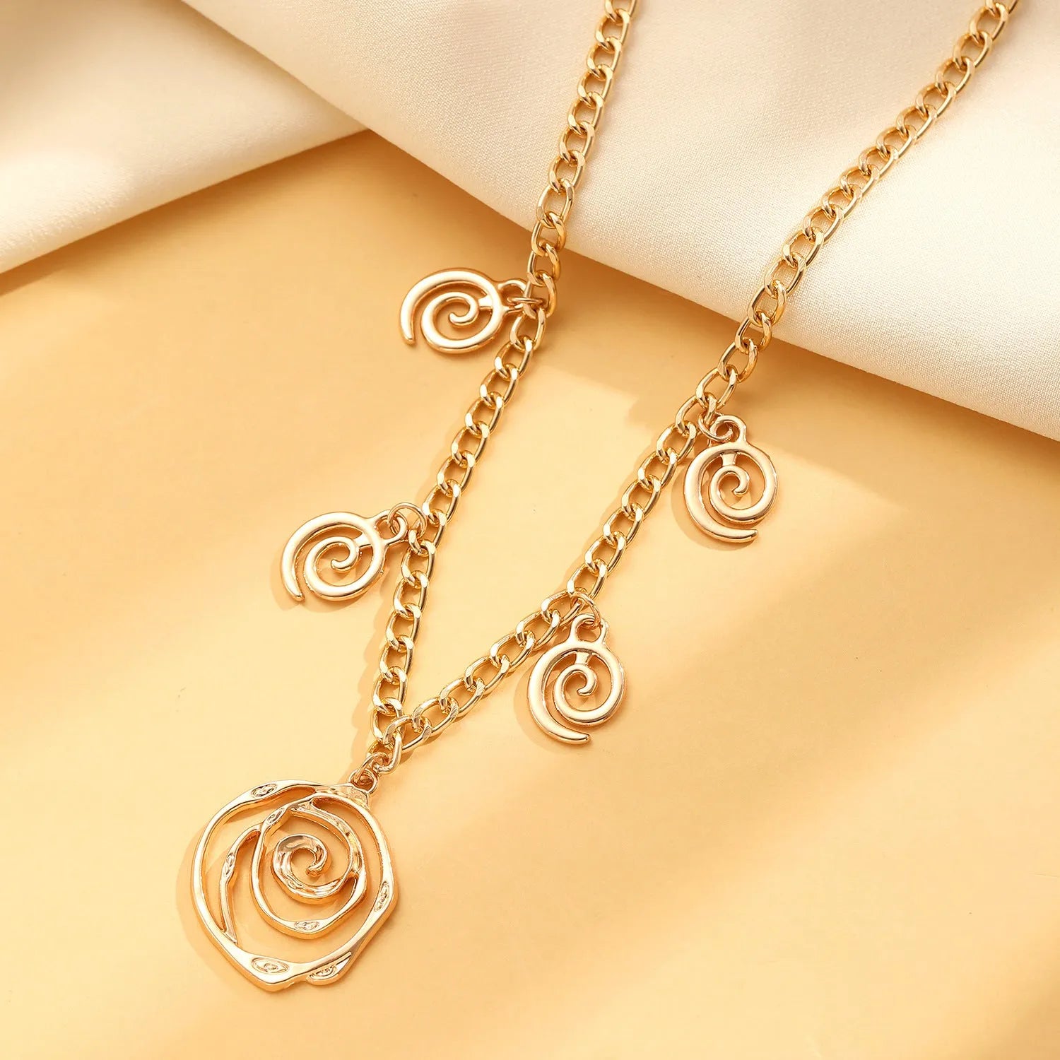 Spiral donut jewellery set showing gold tone necklace, bracelet and earrings with geometric circular design