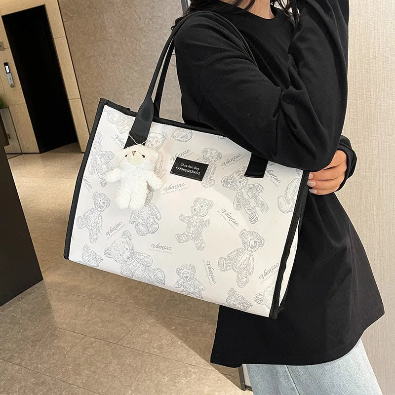 Women's black canvas tote bag with rhombus print pattern showing horizontal square shape and shoulder strap