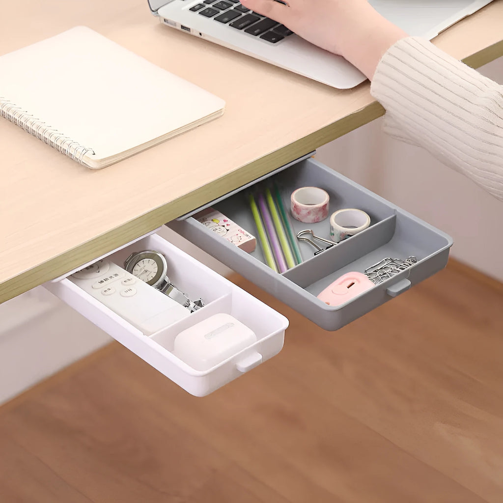 White plastic adhesive under desk storage drawer box with a lid and internal divider grid for organisation.