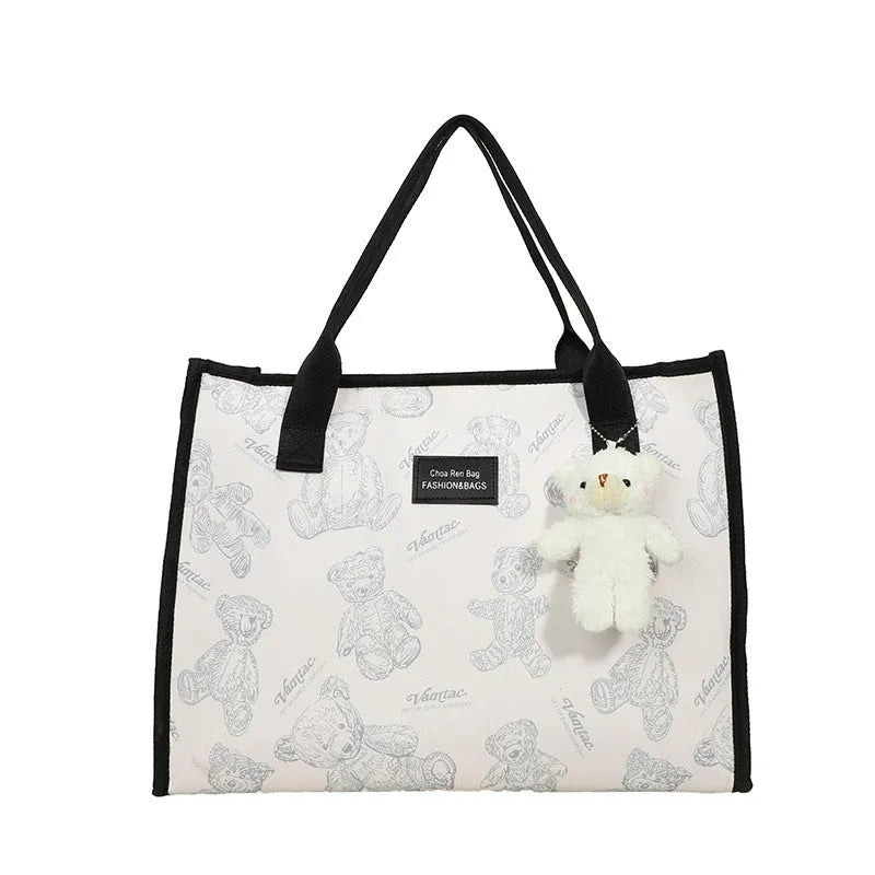 Women's black canvas tote bag with rhombus print pattern showing horizontal square shape and shoulder strap