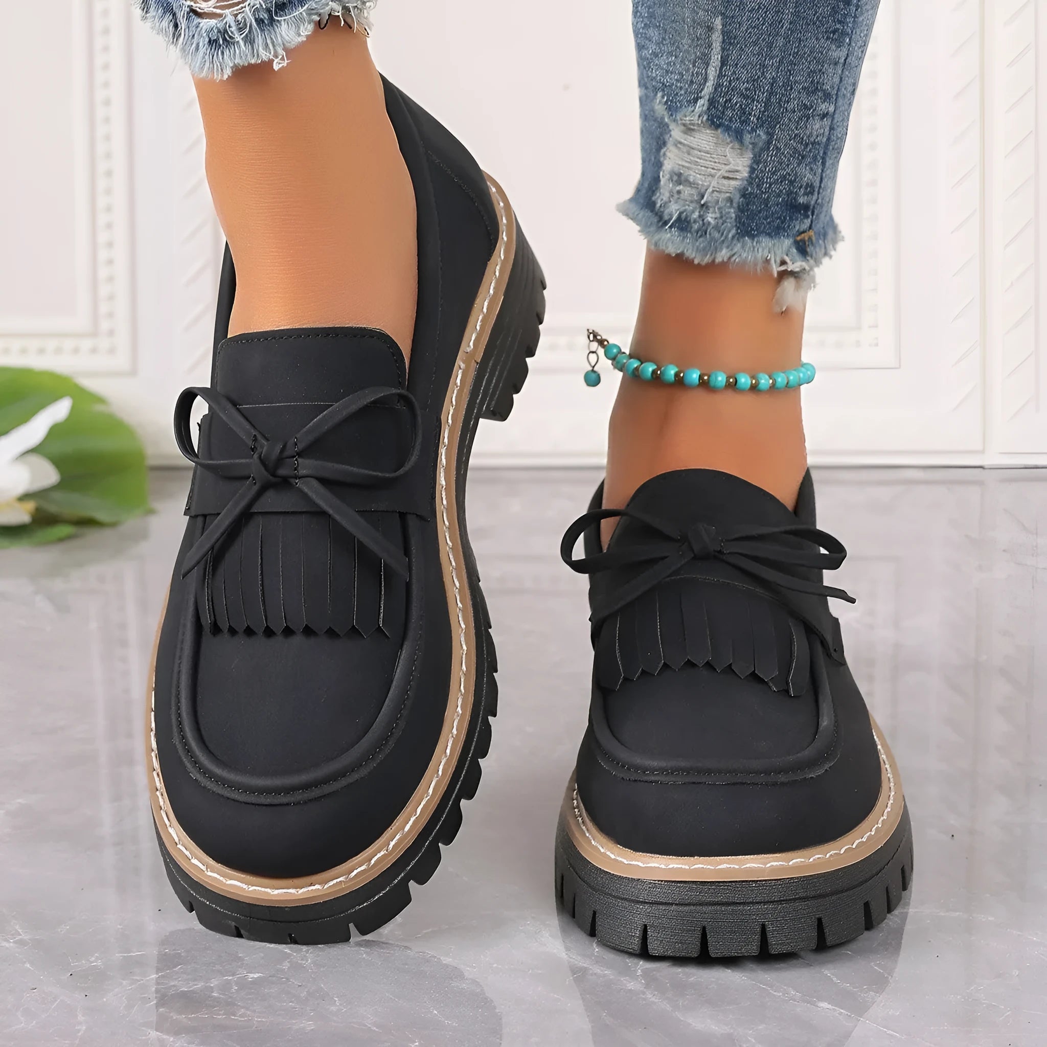 Women's black plus size loafers with tassel decoration and a chunky rubber sole.