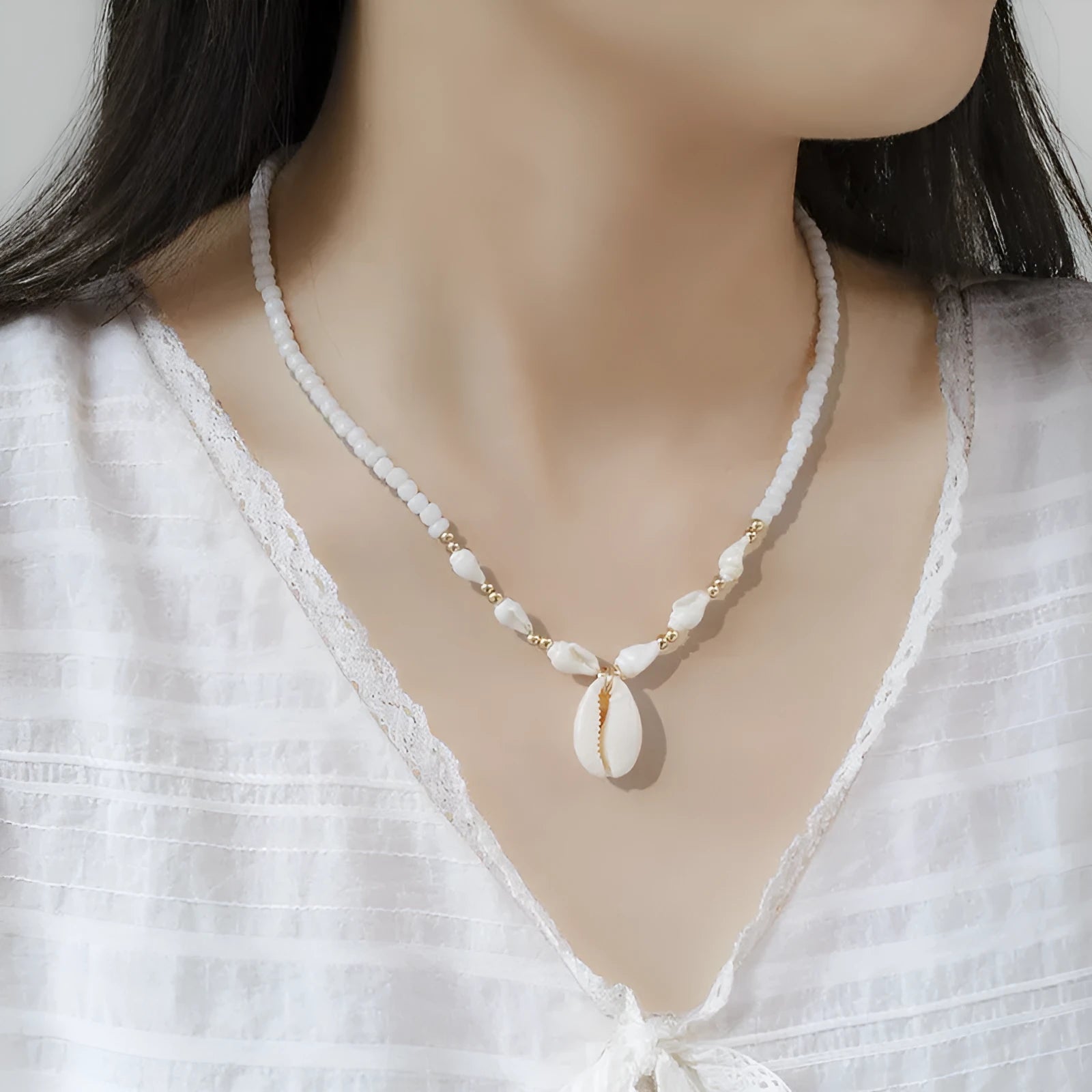 White shell bead necklace with a mother pearl pendant on a silver-toned chain.