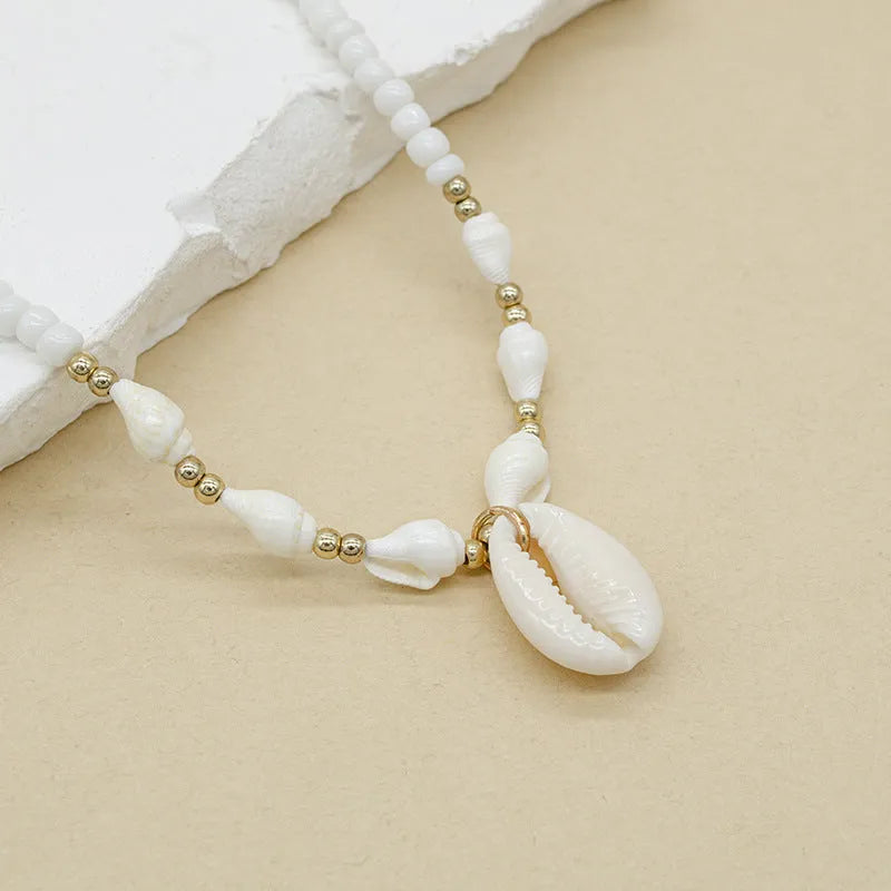 White shell bead necklace with a mother pearl pendant on a silver-toned chain.