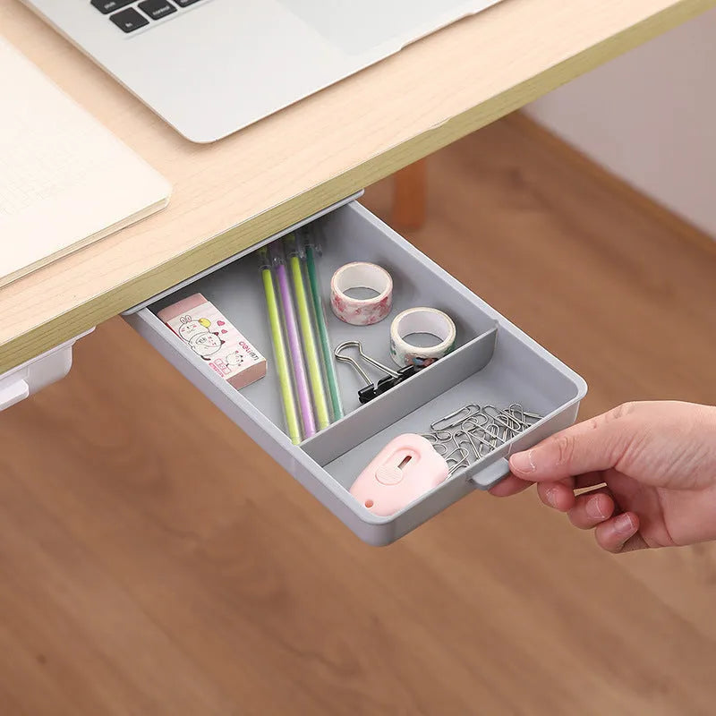 White plastic adhesive under desk storage drawer box with a lid and internal divider grid for organisation.