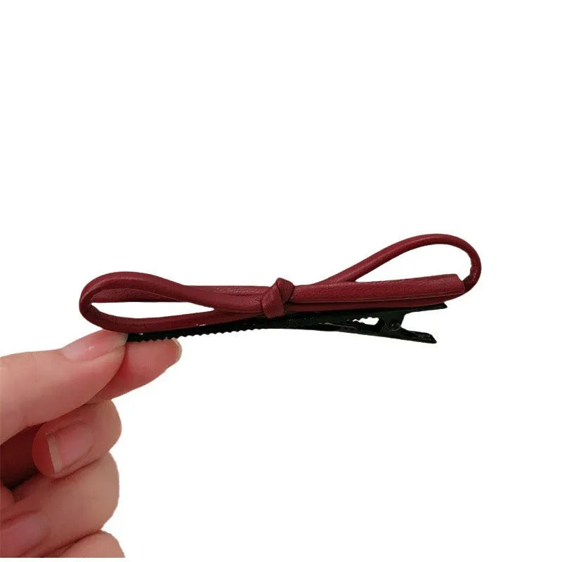 Wine red leather bow-shaped hair barrette on a white background.