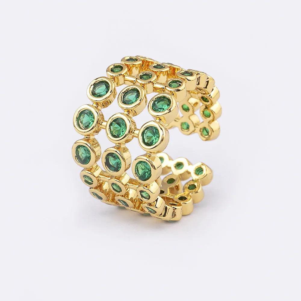 Copper ring with 18K gold plating and large green zirconia stones in an exaggerated wide-band design.