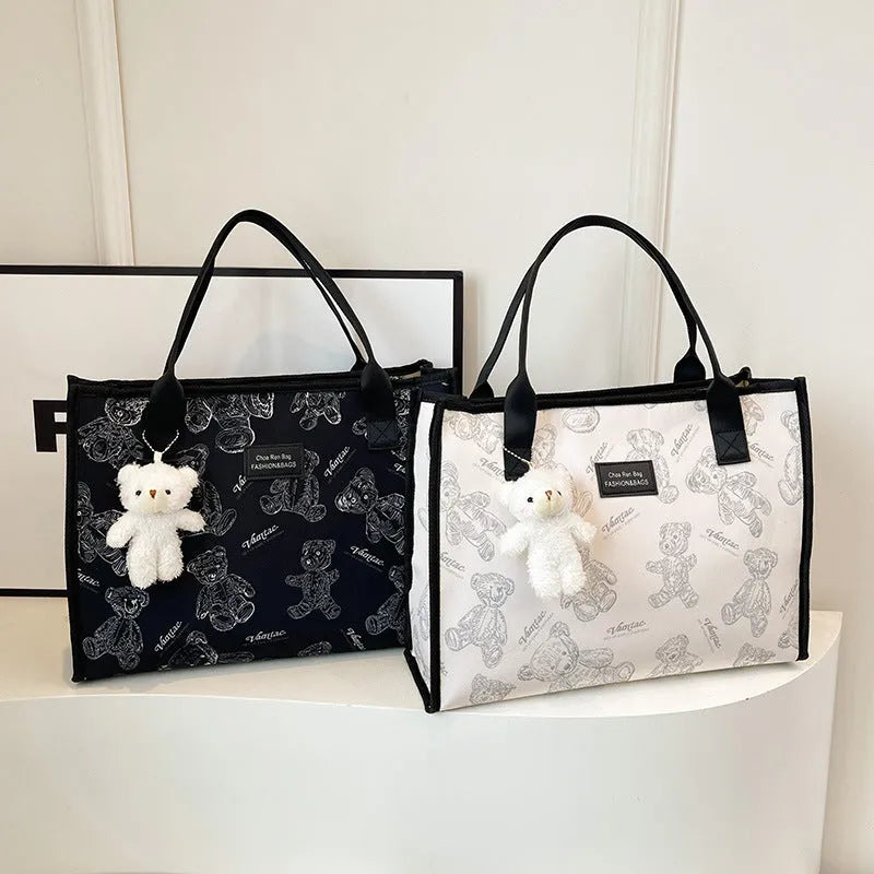 Women's black canvas tote bag with rhombus print pattern showing horizontal square shape and shoulder strap