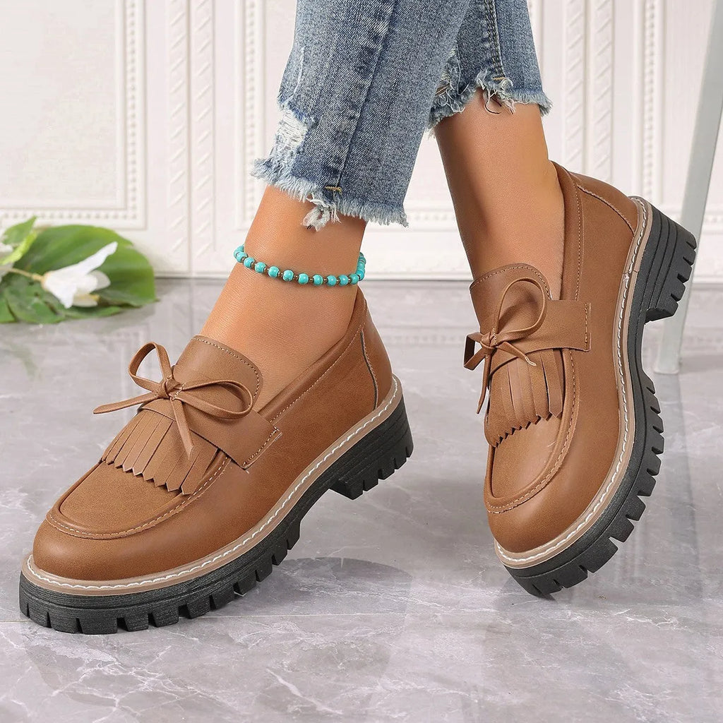 Women's black plus size loafers with tassel decoration and a chunky rubber sole.