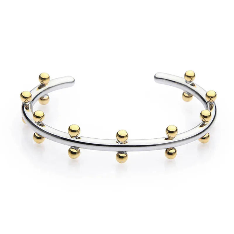 Stainless steel bracelet with C-shaped bean bead charm featuring texture and rivet details.