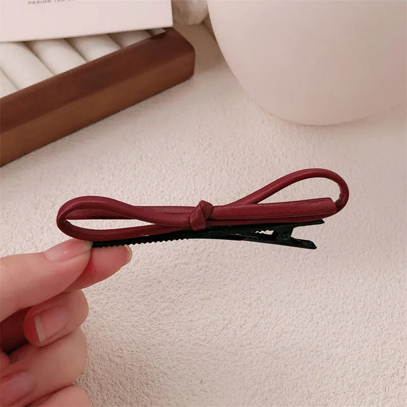Wine red leather bow-shaped hair barrette on a white background.