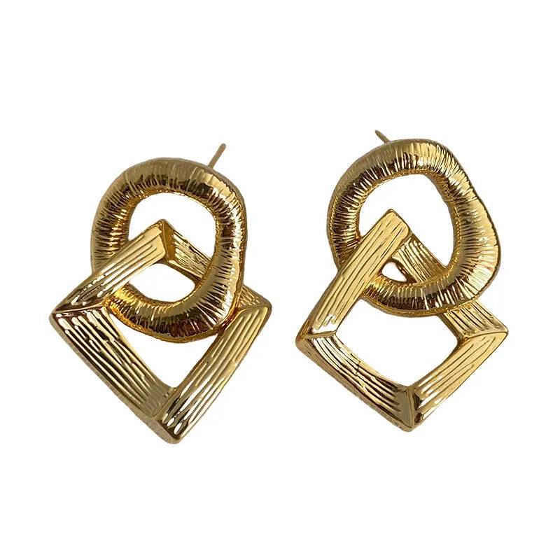 Geometric retro-style drop earrings with a circular pendant, available in gold and silver.