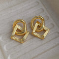 Geometric retro-style drop earrings with a circular pendant, available in gold and silver.
