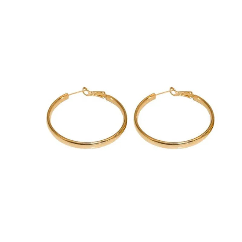 A pair of 40mm circular metal earrings in a gold or silver electroplated finish on a copper base