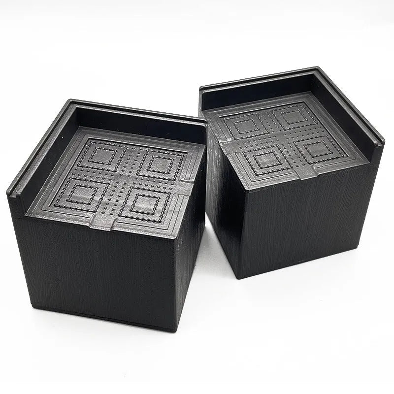 Four black plastic circular furniture riser feet on a floor