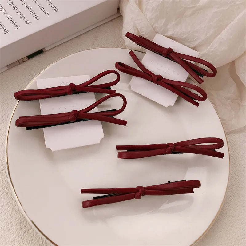 Wine red leather bow-shaped hair barrette on a white background.