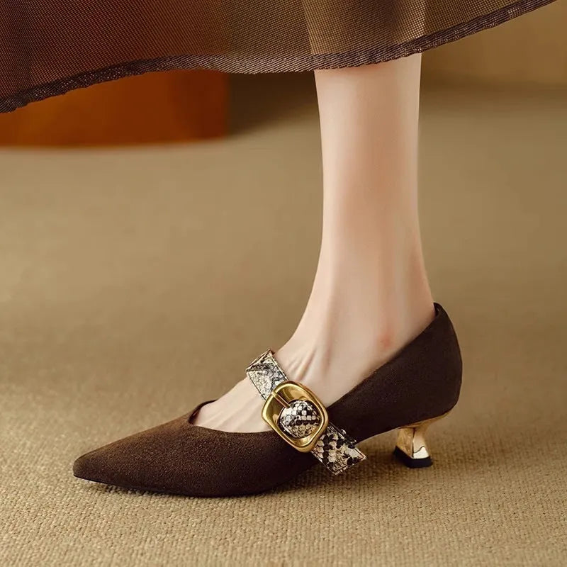 Women's black pointed toe high heels with a buckle and stiletto heel on a white background.