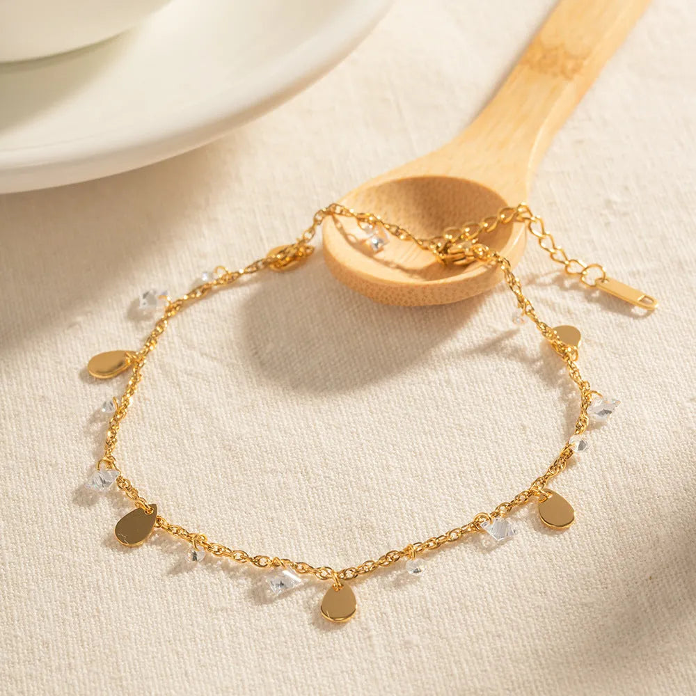Close-up of a stainless steel geometric anklet with a personalised water drop tassel pendant.