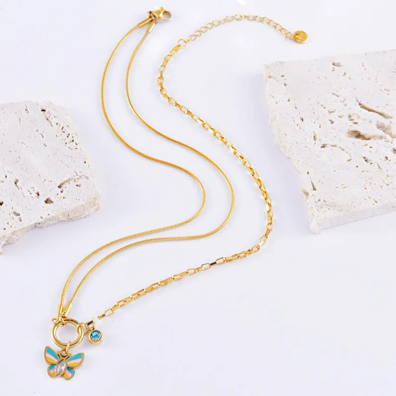 Gold-coloured titanium steel butterfly jewellery set with necklace and bracelet showing epoxy resin pendants