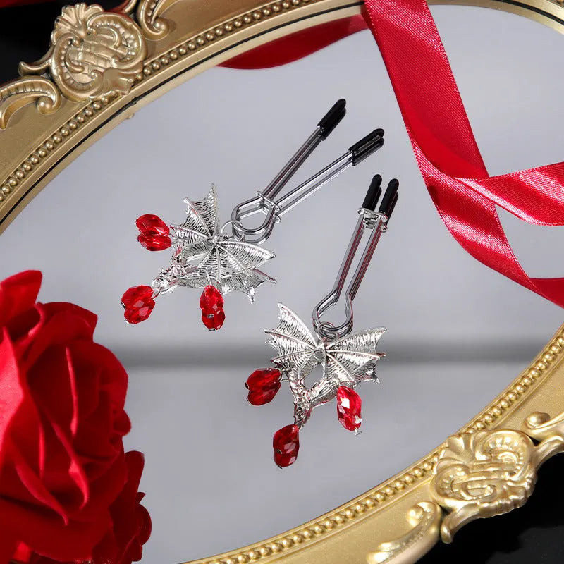 Silver bat-shaped adjustable nipple clamps with ruby decoration on a black background