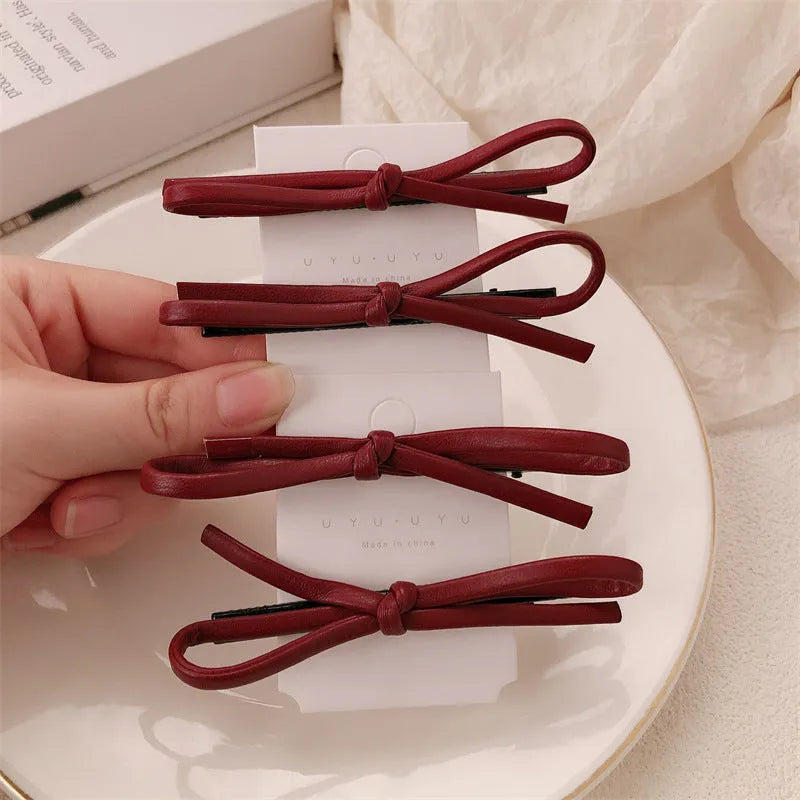 Wine red leather bow-shaped hair barrette on a white background.