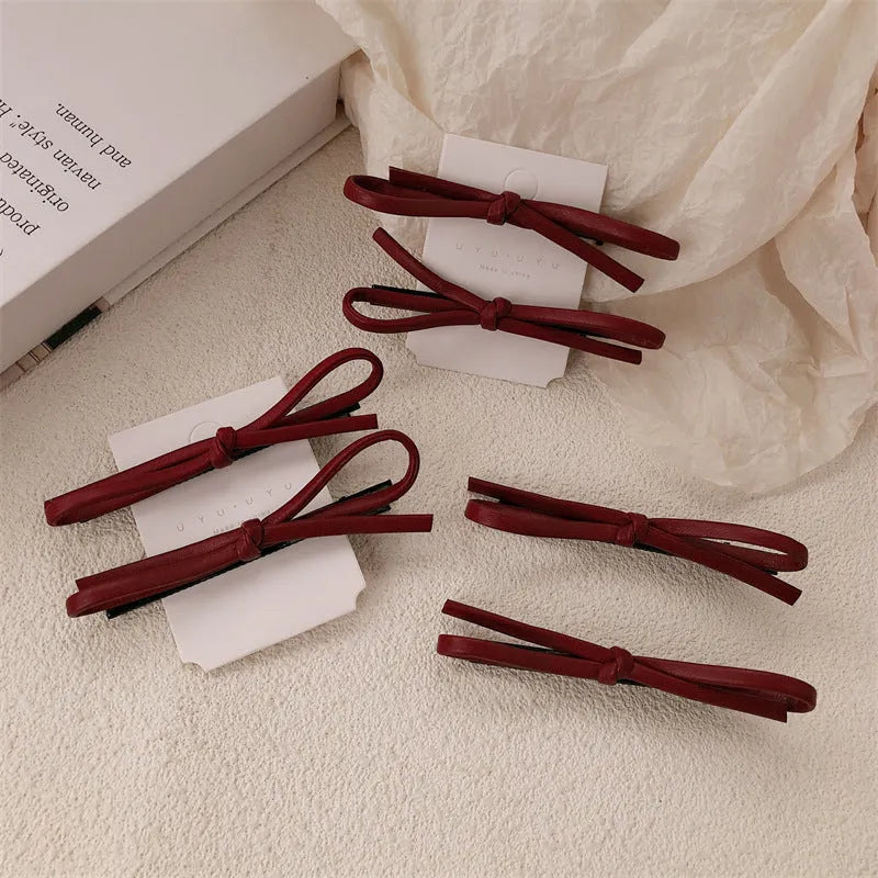 Wine red leather bow-shaped hair barrette on a white background.
