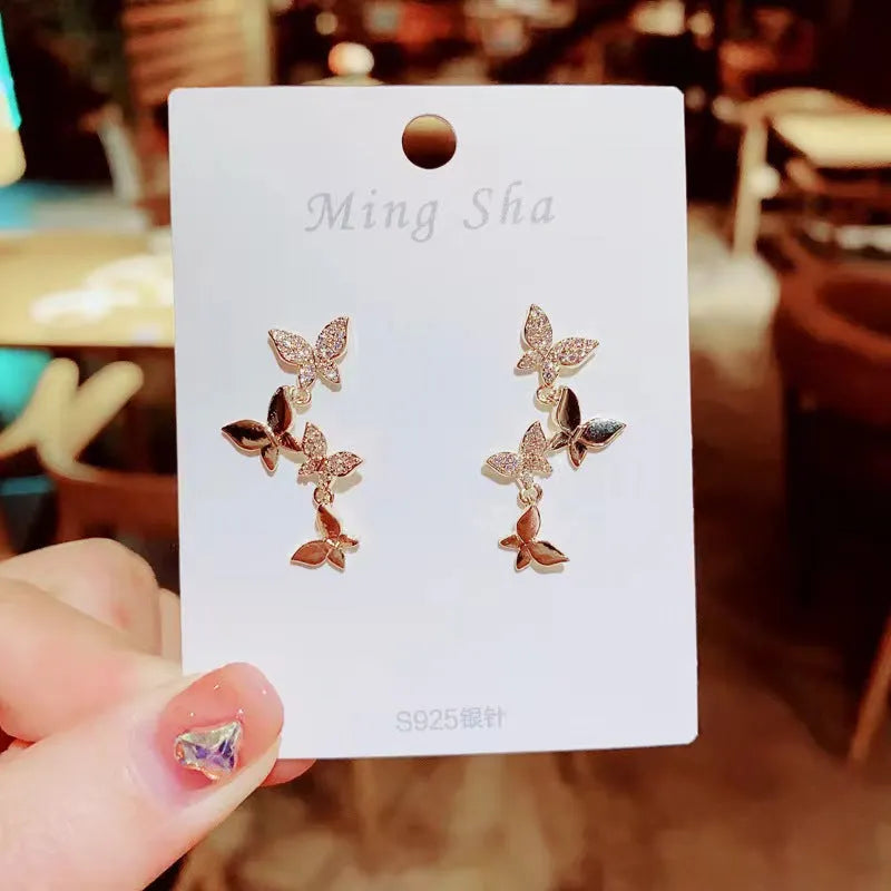Women's butterfly drop earrings in copper with gold finish showing four butterfly design