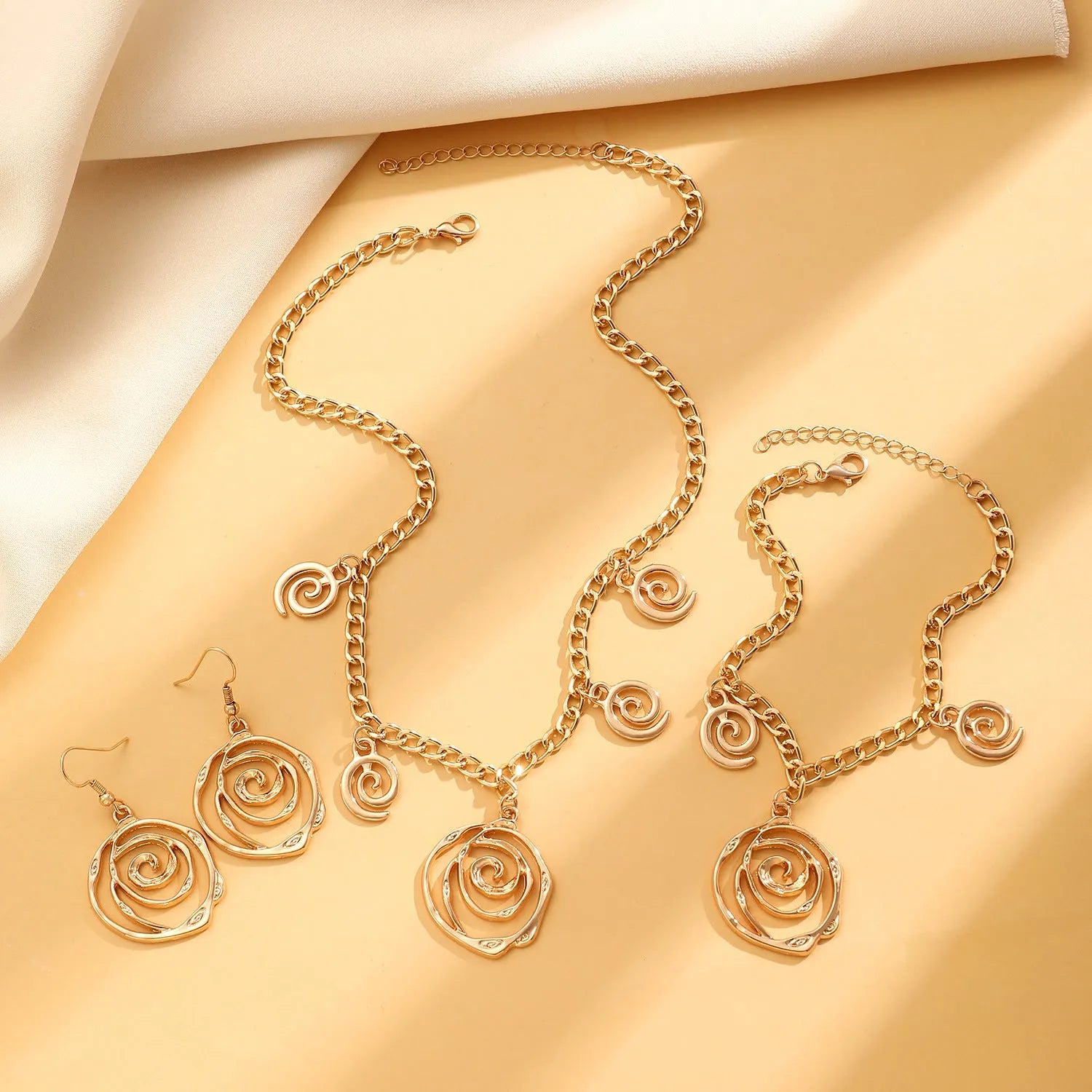 Spiral donut jewellery set showing gold tone necklace, bracelet and earrings with geometric circular design