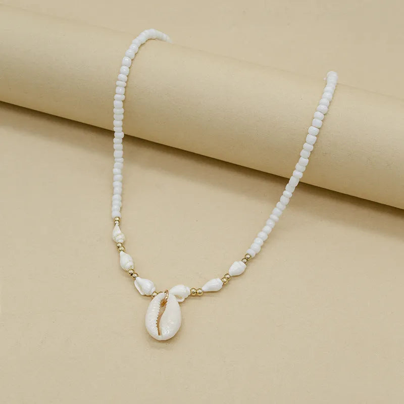 White shell bead necklace with a mother pearl pendant on a silver-toned chain.