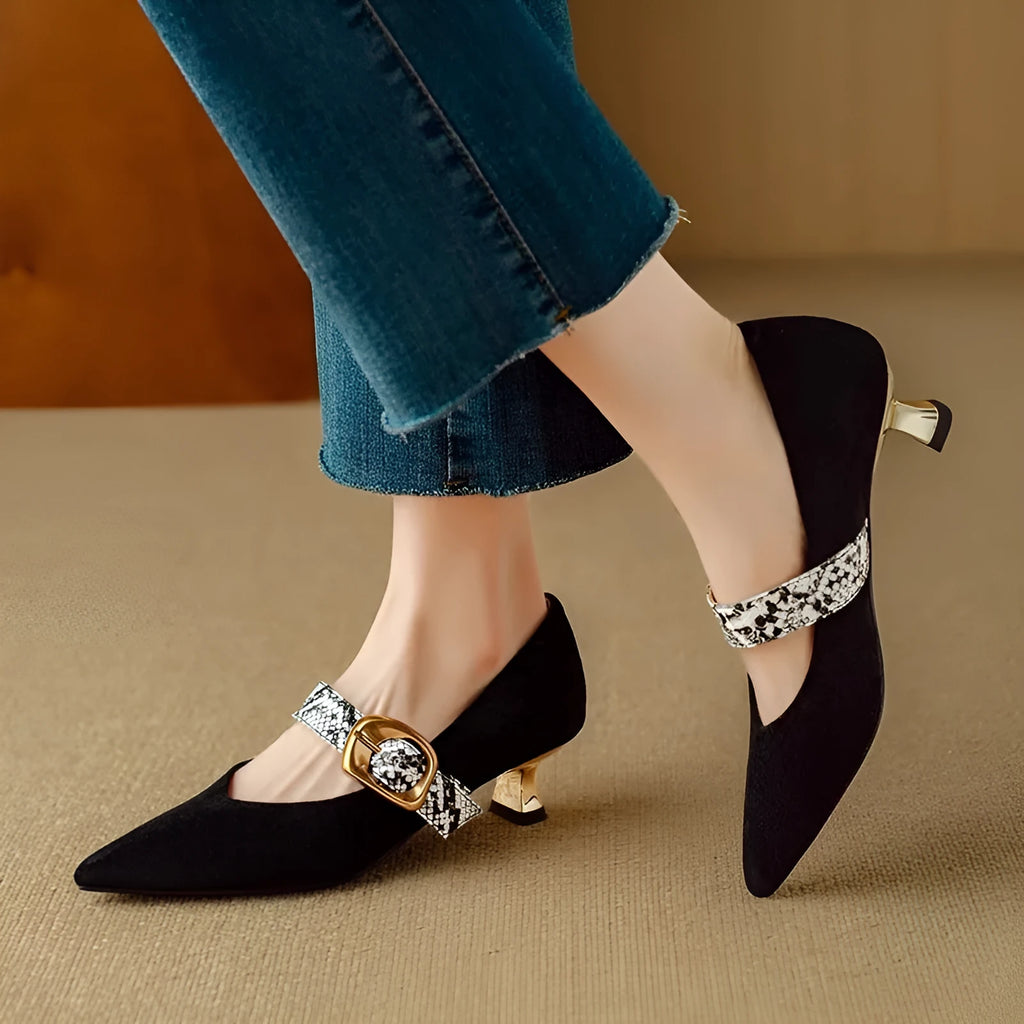 Women's black pointed toe high heels with a buckle and stiletto heel on a white background.