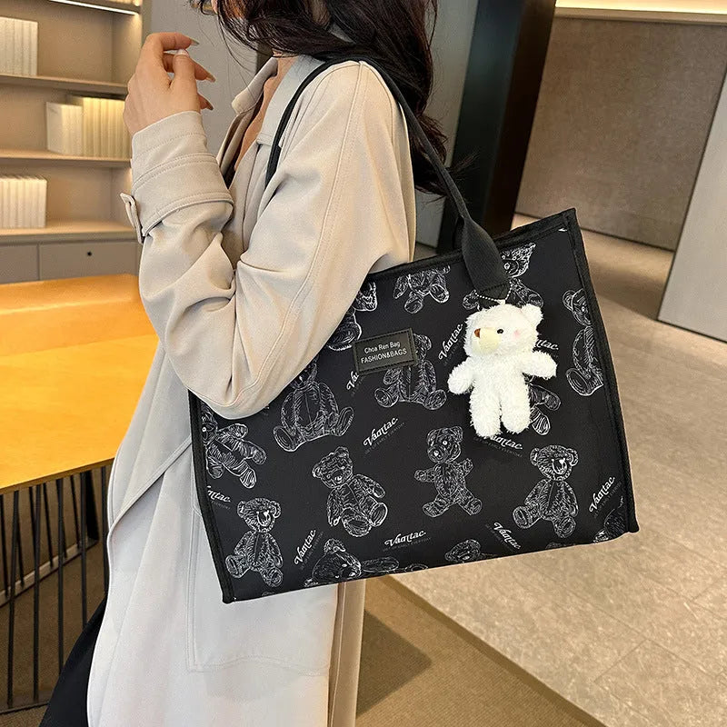 Women's black canvas tote bag with rhombus print pattern showing horizontal square shape and shoulder strap