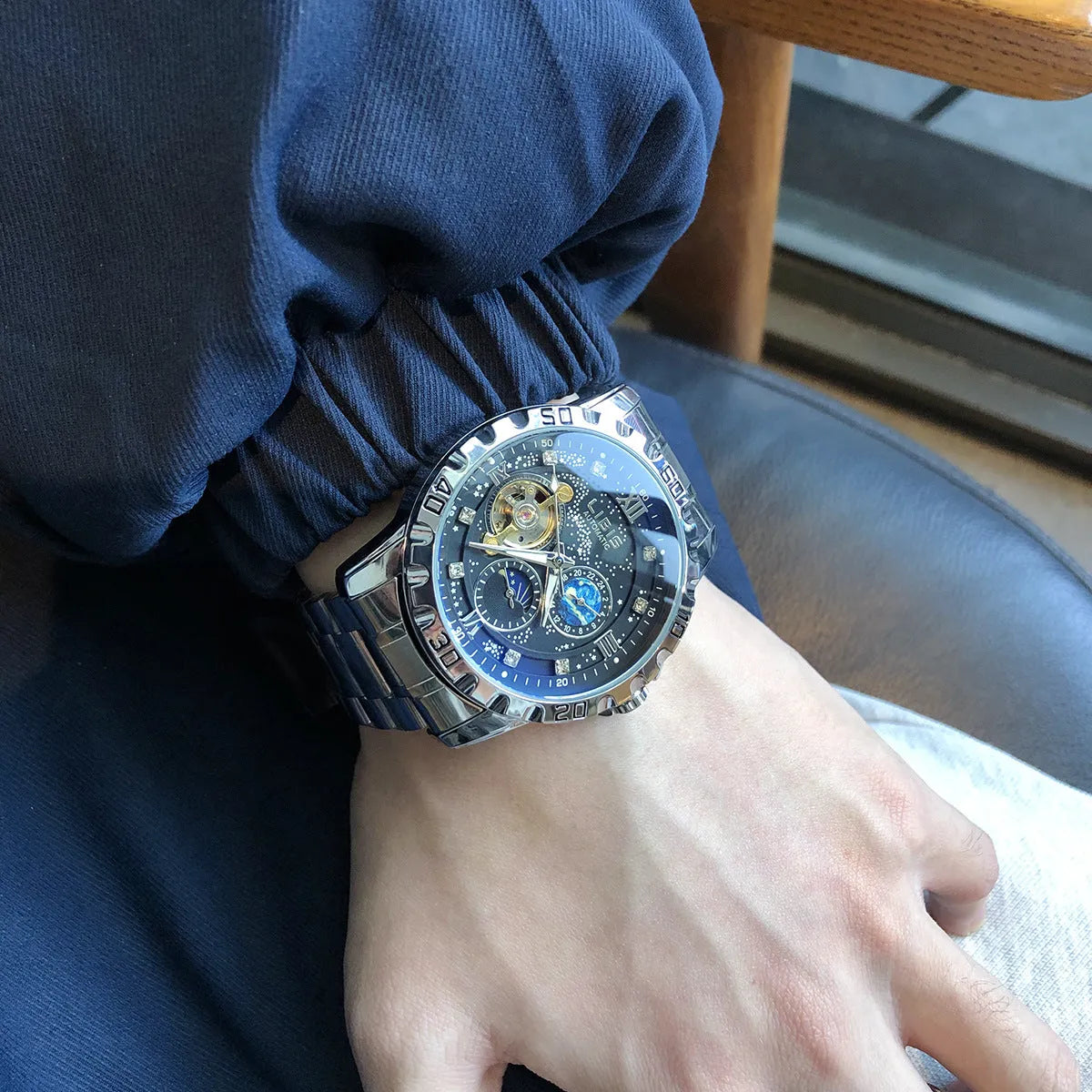 Men's silver automatic watch with black starry luminous dial on a steel bracelet