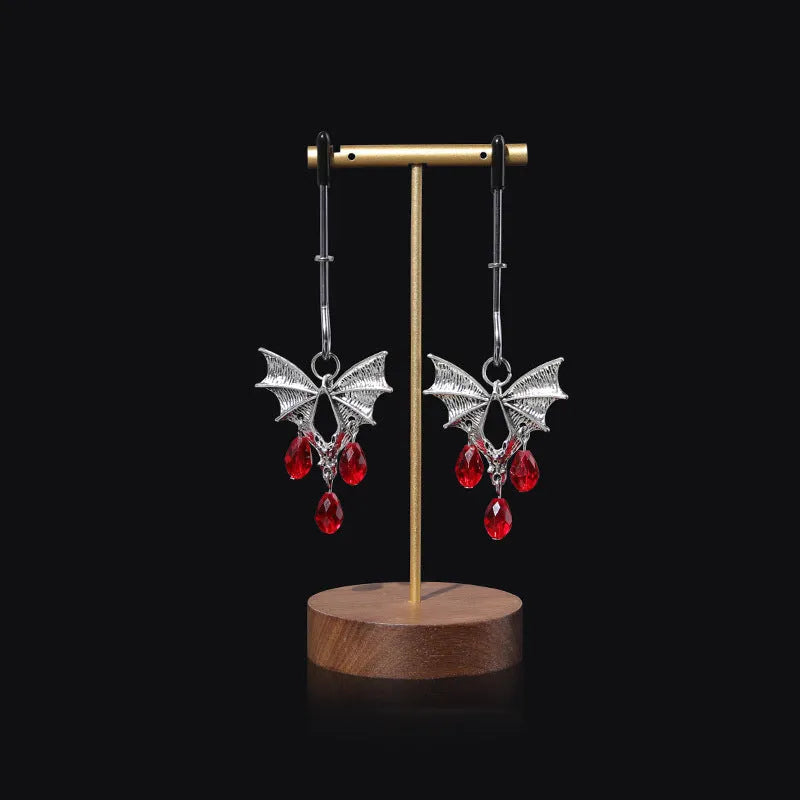 Silver bat-shaped adjustable nipple clamps with ruby decoration on a black background