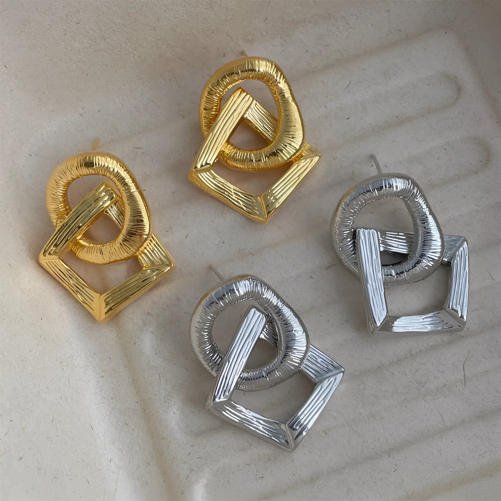 Geometric retro-style drop earrings with a circular pendant, available in gold and silver.