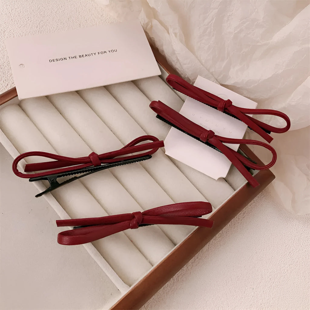 Wine red leather bow-shaped hair barrette on a white background.