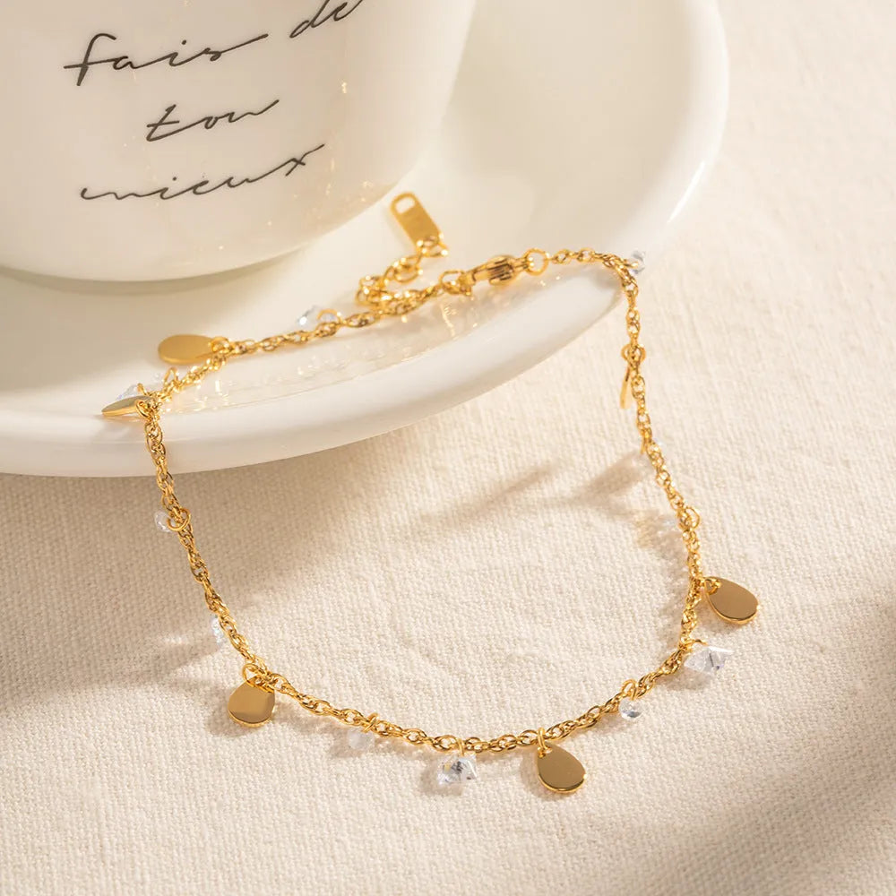 Close-up of a stainless steel geometric anklet with a personalised water drop tassel pendant.