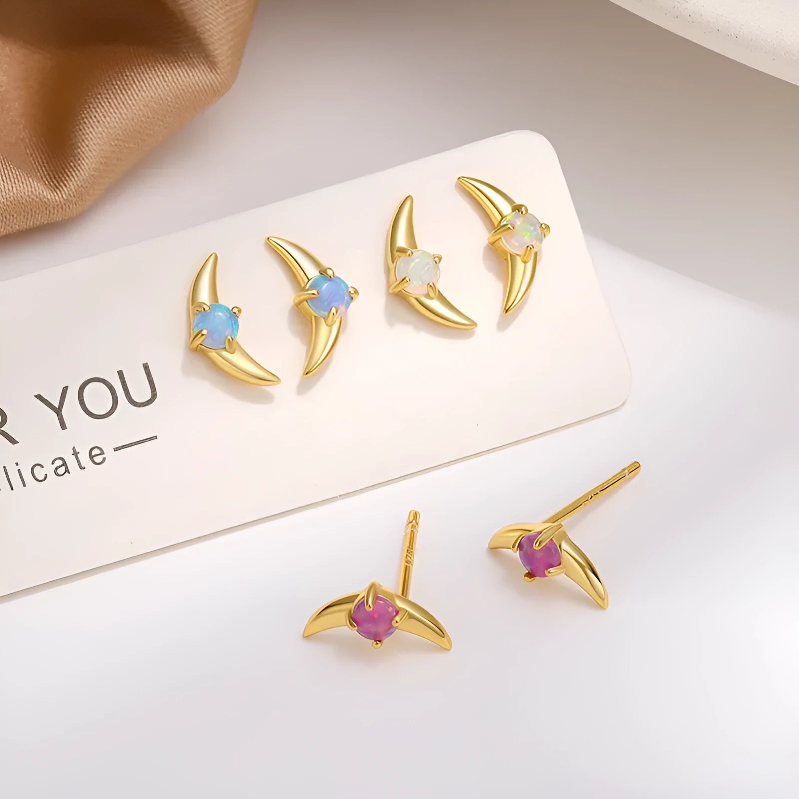 A pair of geometric-shaped 925 silver earrings with a gold colour electroplate and a blue cubic zirconia stone.