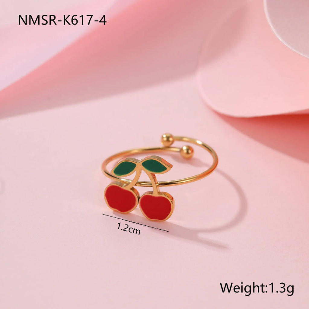 Cherry-themed jewellery set with gold-plated necklace, bracelet, earrings, and ring on stainless steel chains.