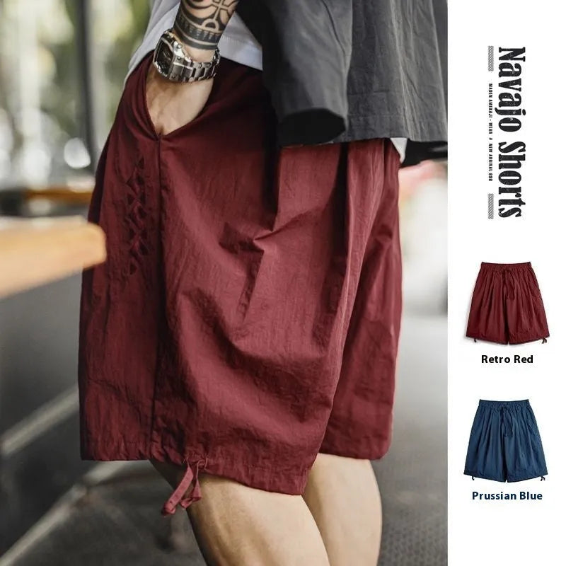 Men's loose fit Prussian blue nylon beach shorts with summer embroidery on a white background.