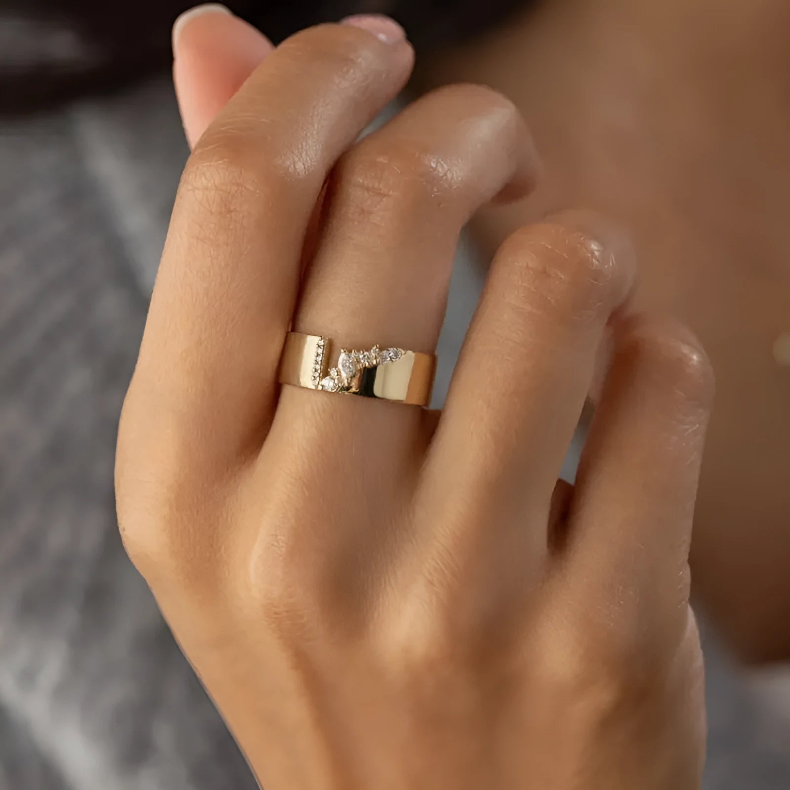 Gold-coloured copper ring with a shining zircon stone on a model's hand.