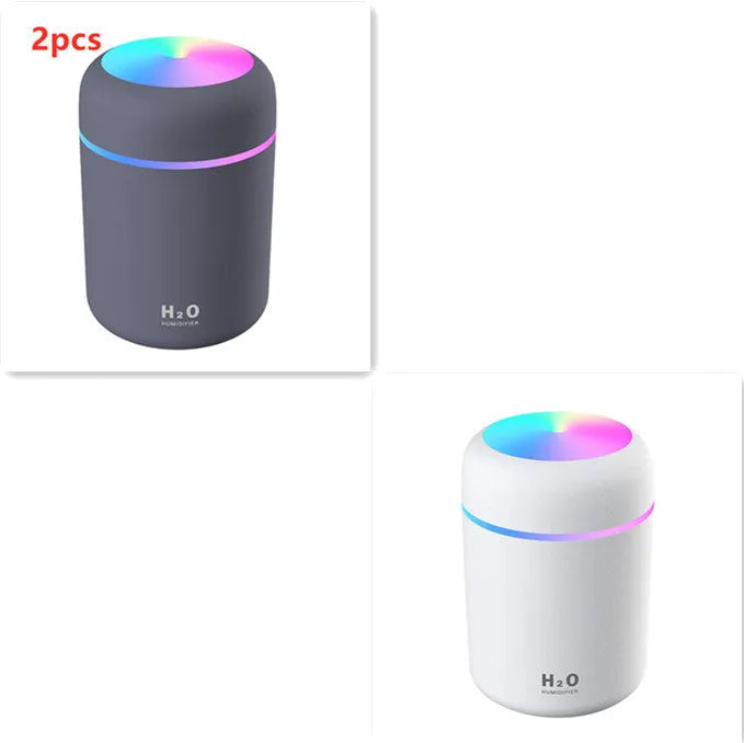 Pink USB desktop humidifier with coloured lights and water tank on a wooden desk