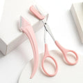 Close-up of a white and pink eyebrow trimming knife with a small curved plastic comb on a plain background.