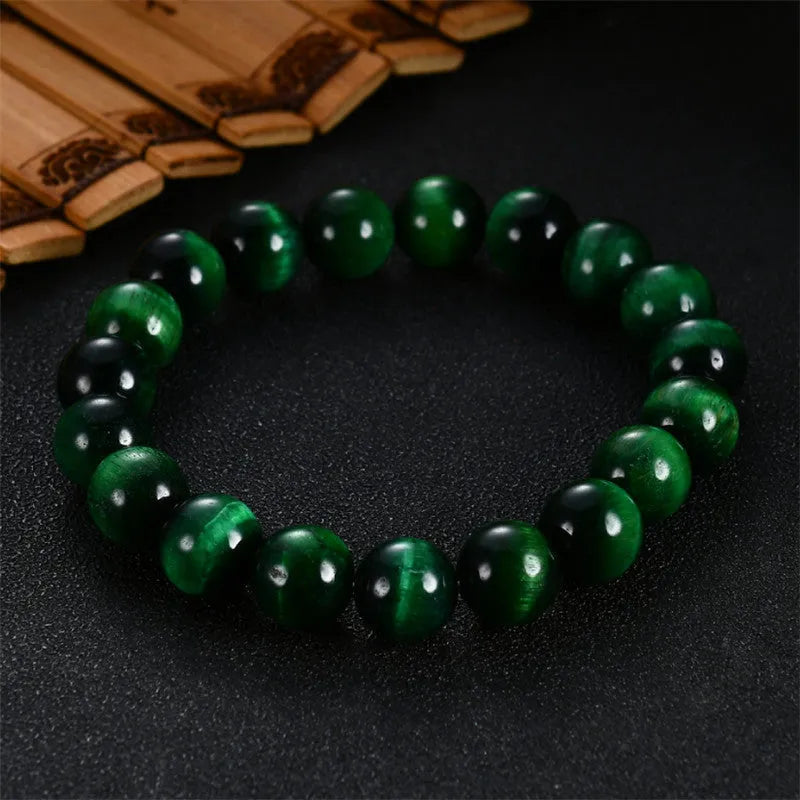 Polished green tiger eye stone bead bracelet on a wrist, showing geometric bead shapes.
